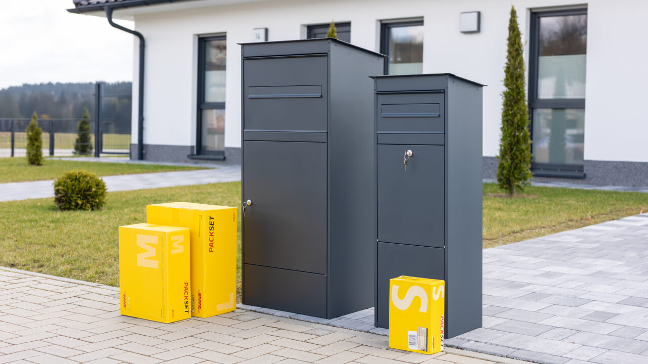 Paketbox JASPER und JASPER XL in Anthrazit vor einem Einfamilienhaus