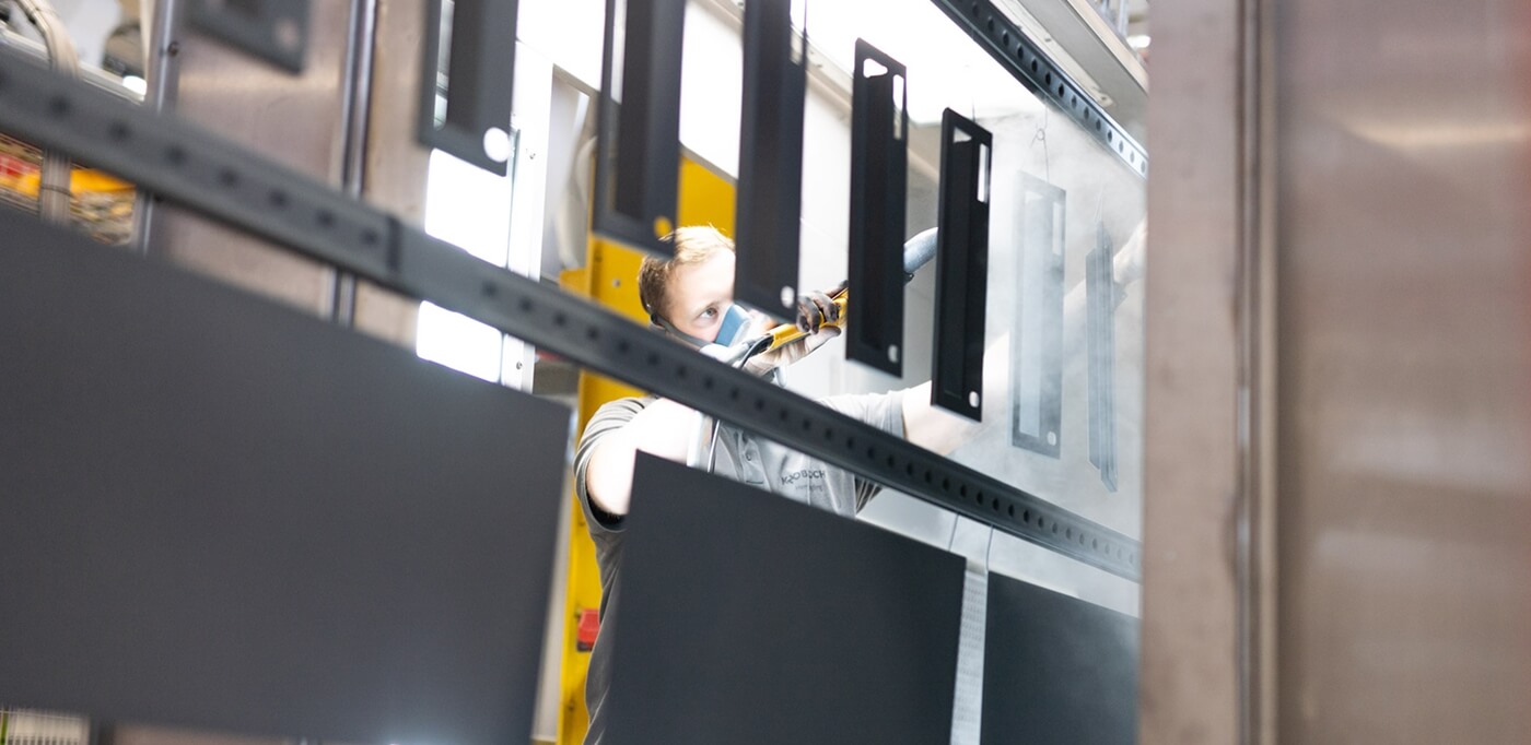 KNOBLOCH Mitarbeiter lackiert Einzelteile einer Briefkastenanlage